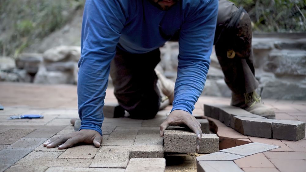 hardscape contractor laying down bricks for outdoor project